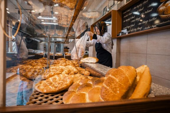 A baker standing behind a display case of fresh bread in a local bakery shop